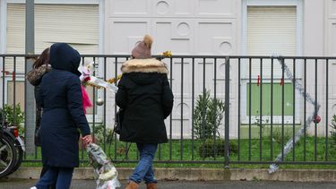 La gente lleva ramos de flores al piso donde se descubrieron los cuerpos de una mujer y sus cuatro hijos, en Meaux, al este de París, el 26 de diciembre de 2023.