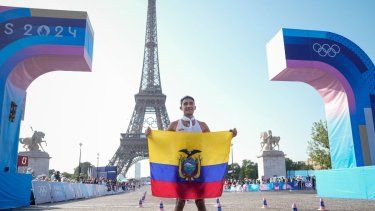 El ecuatoriano Brian Daniel Pintado posa con la bandera de su país frente a la torre Eiffel tras cruzar primero la meta de la prueba de 20km de marcha atlética, en los Juegos de París, el 1 de agosto de 2024.&nbsp;