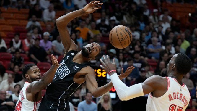 Haywood Highsmith, izquierda, del Heat de Miami le quita el balón a Kevin Durant, al centro, de los Nets de Brooklyn, mientras Bam Adebayo (13) intenta controlarlo durante la primera mitad del partido entre ambos equipos, el domingo 8 de enero de 2023.