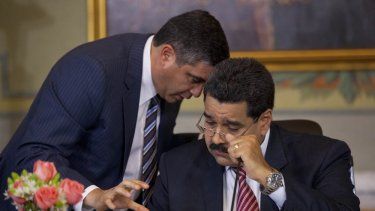 El Ministro del Interior y Justicia de Venezuela, Miguel Rodríguez Torres, a la izquierda, habla con el dictador Nicolás Maduro durante una conferencia de prensa con los medios nacionales y extranjeros en el Palacio Presidencial de Miraflores en Caracas, Venezuela en 2014.