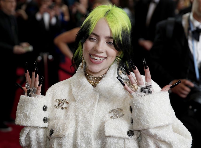 La cantante Billie Eilish, con el cabello teñido de verde fosforescente, lleva un abrigo color blanco de la firma Chanel.  