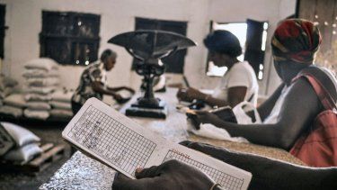 Unas personas esperan comida en una tienda, mientras una de ellas sostiene una libreta, una tarjeta de racionamiento que desde 1963 permite a los cubanos comprar alimentos básicos. 