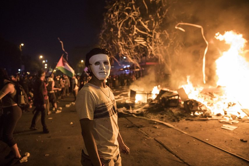 Un manifestante antigubernamental enmascarado se encuentra junto a una barricada en llamas en Santiago de Chile, el lunes 28 de octubre de 2019.