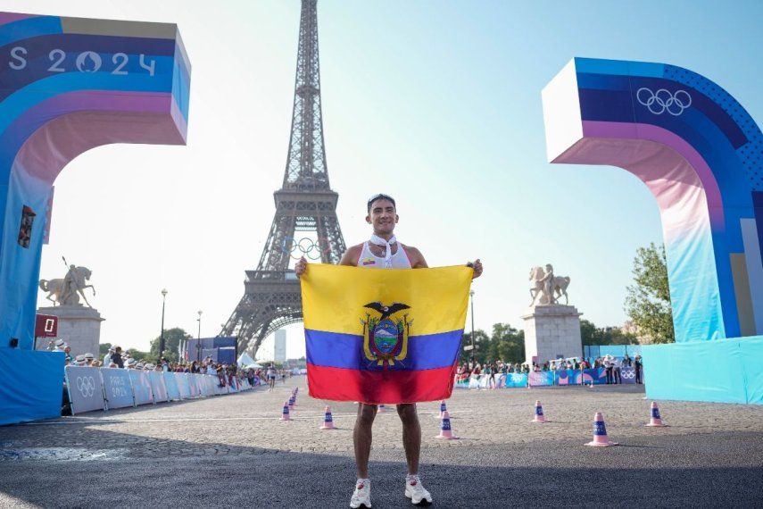 El ecuatoriano Brian Daniel Pintado posa con la bandera de su país frente a la torre Eiffel tras cruzar primero la meta de la prueba de 20km de marcha atlética, en los Juegos de París, el 1 de agosto de 2024.&nbsp;