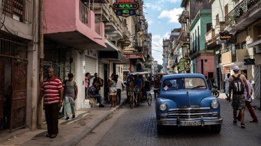 Varias personas caminan bajo el cartel que anuncia la existencia de una tienda de comestibles privada en La Habana, Cuba, el 11 de noviembre de 2023.