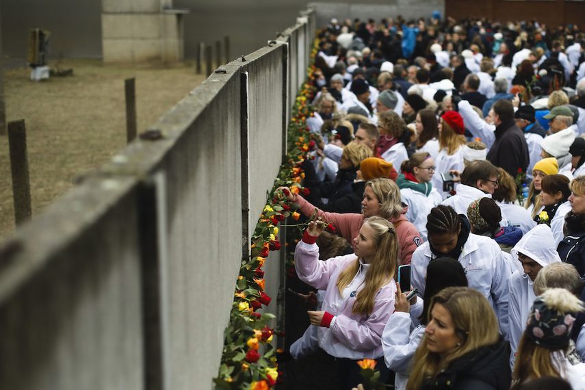 Personas colocan rosas en lo que queda en pie del Muro de Berl&iacute;n durante una ceremonia para conmemorar el 30 aniversario de la ca&iacute;da del muro en el memorial en Bernauer Strasse en Berl&iacute;n, el s&aacute;bado 9 de noviembre de 2019.&nbsp;