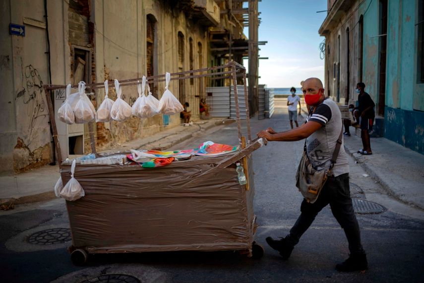 Un vendedor ambulante con una máscara como medida de precaución contra la propagación del coronavirus empuja su carro por una calle en La Habana, Cuba, el lunes 31 de agosto de 2020.