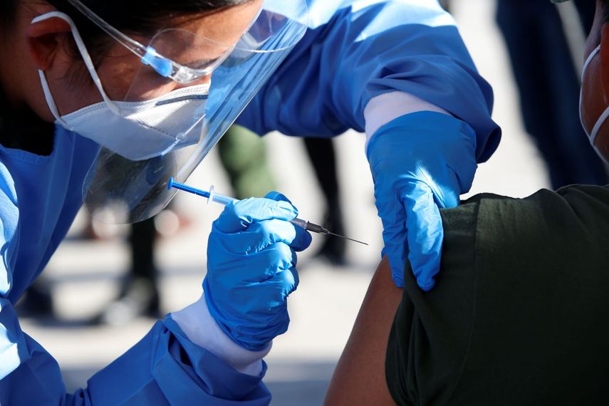Una empleada de salud aplica una vacuna anticovid.