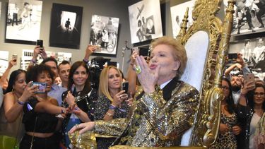 El astr&oacute;logo Walter Mercado lanza besos al p&uacute;blico desde el trono sobre ruedas en el que era trasladado en el History Miami Museum, donde expone 50 a&ntilde;os de su vida.&nbsp;