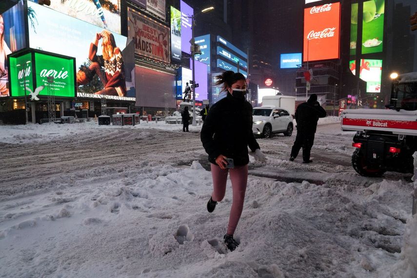 Una mujer trota durante una nevada la noche del jueves 17 de diciembre de 2020, en Times Square, en la ciudad de Nueva York.&nbsp;