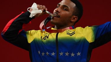 El venezolano Julio Rubén Mayora Pernia posa con su medalla de plata en el podio de la ceremonia de victoria de la competencia de halterofilia masculina de 73 kg durante los Juegos Olímpicos de Tokio 2020