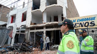 Policías vigilan los restos de una vivienda que sufrió un ataque con dinamita durante enfrentamientos entre organizaciones criminales en la ciudad de Trujillo, norte de Perú, el 15 de agosto de 2025.