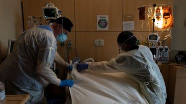 El neumólogo Frans Oudenaar, a la izquierda, y el enfermero Bryan Hofilena cubren el cuerpo de un paciente con COVID-19 con una sábana.