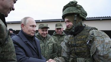 El presidente de Rusia, Vladimir Putin estrecha la mano de un soldado durante una visita a un centro de instrucción militar en el Distrito Militar Occidental para reservistas movilizados, mientras el ministro ruso de Defensa, Sergei Shoigu, en el centro, sonríe, en la región de Ryazan, Rusia, el jueves 20 de octubre de 2022.