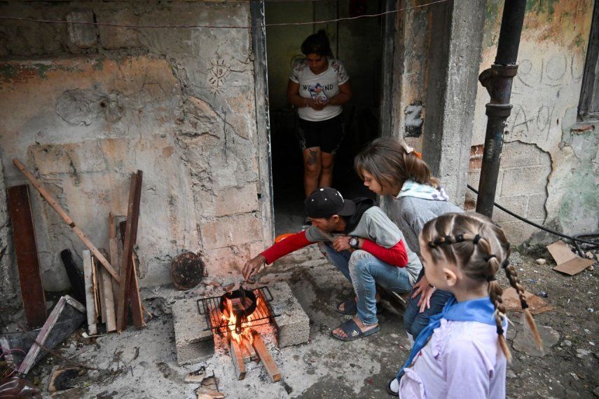 Un hombre cocina salchichas sobre un fuego de leña junto a su esposa e hijas durante un corte de electricidad en el barrio de Poey en La Habana.
