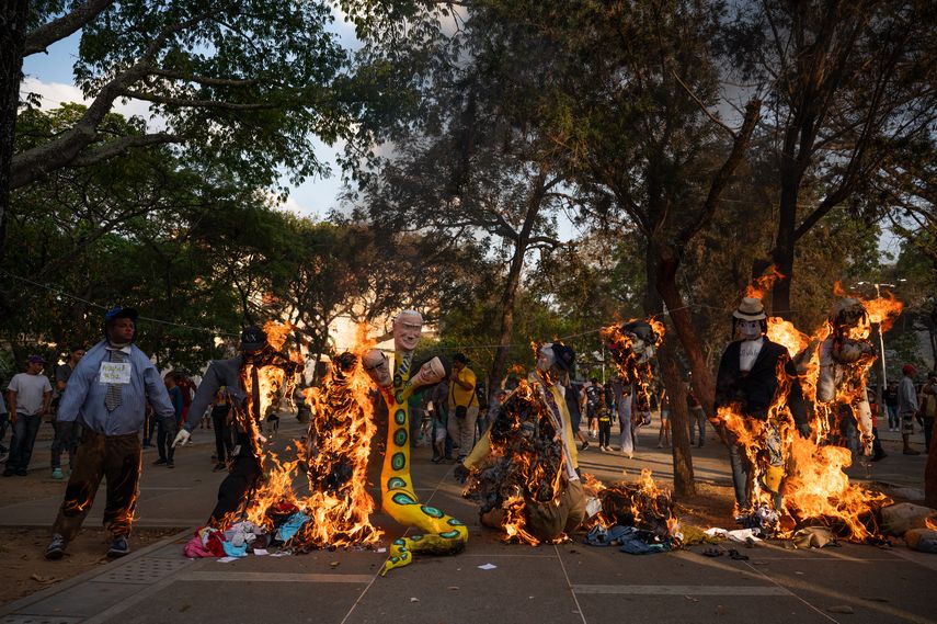 Muñecos que representan, de izquierda a derecha, al diputado venezolano por el partido PSUV Hugbel Roa, la exmáxima autoridad en políticas de criptomonedas en Venezuela Joselit Ramírez, el expresidente de la estatal petrolera Pdvsa, Rafael Ramírez, político venezolano corrupto y antivalores son quemados durante el tradicional ritual de la Quema de Judas en Caracas el 9 de abril de 2023.