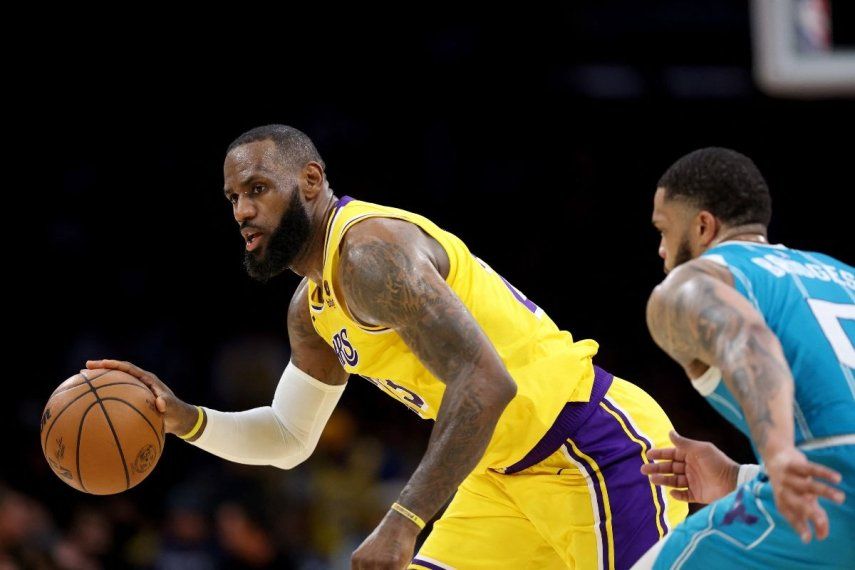 LeBron James (izquierda), de los Lakers de Los Ángeles, maneja el balón en un partido contra los Hornets de Charlotte, el 28 de diciembre de 2023.