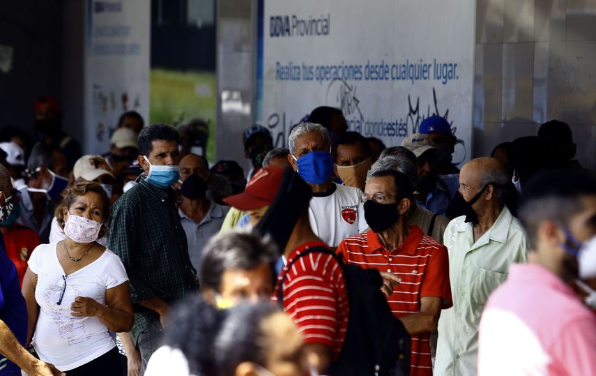 Personas esperan en la puerta de una entidad bancaria en Valencia, Venezuela, en medio de la pandemia de COVID-19. El régimen y la oposición acordaron un plan para enfrentar la pandemia, con la mediación de la OPS.