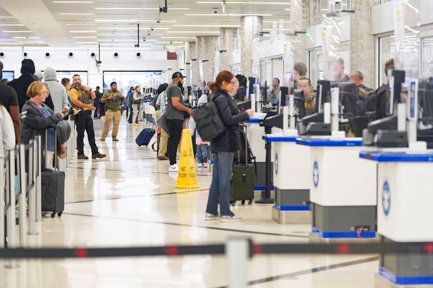 Un agente de ICE dirige a los pasajeros mientras otros agentes de ICE y miembros de la TSA revisan las identificaciones en el mostrador de seguridad de la TSA en el Aeropuerto Internacional Hartsfield-Jackson de Atlanta el 28 de marzo de 2026 en Atlanta, Georgia.