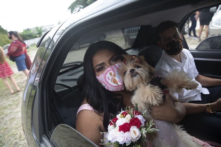 Con mascarillas para protegerse del coronavirus, Erica da Concei&ccedil;ao y Joao Blank se sientan en el asiento trasero de un auto para una boda en un drive-thru en el registro del vecindario de Santa Cruz, en R&iacute;o de Janeiro, Brasil, el 28 de mayo de 2020. Un notario presidi&oacute; la ceremonia desde el exterior. No fue el acto rom&aacute;ntico que la pareja hab&iacute;a imaginado, pero era una de sus pocas opciones en plena pandemia del COVID-19.&nbsp;