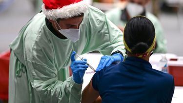 Un trabajador de salud con un gorro de Santa Claus administra una vacuna contra coronavirus a una colega en el Coliseo Pedrín Zorrilla, en San Juan, Puerto Rico, el miércoles 30 de diciembre de 2020.&nbsp;