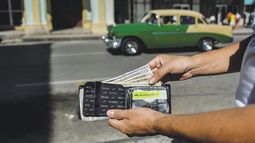 Un hombre muestra varios billetes de dólar en una calle en La Habana .