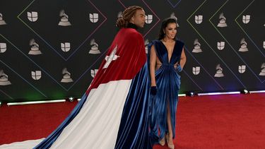Arropado con una bandera cubana, Yotuel, autor de Patria y Vida, arriba junto a su esposa, Beatriz Luengo, al homenaje que la Academia Latina de la Grabación le rindió al salsero panameño Rubén Blades, quien fue nombrado Persona del Año en la edición 2021.