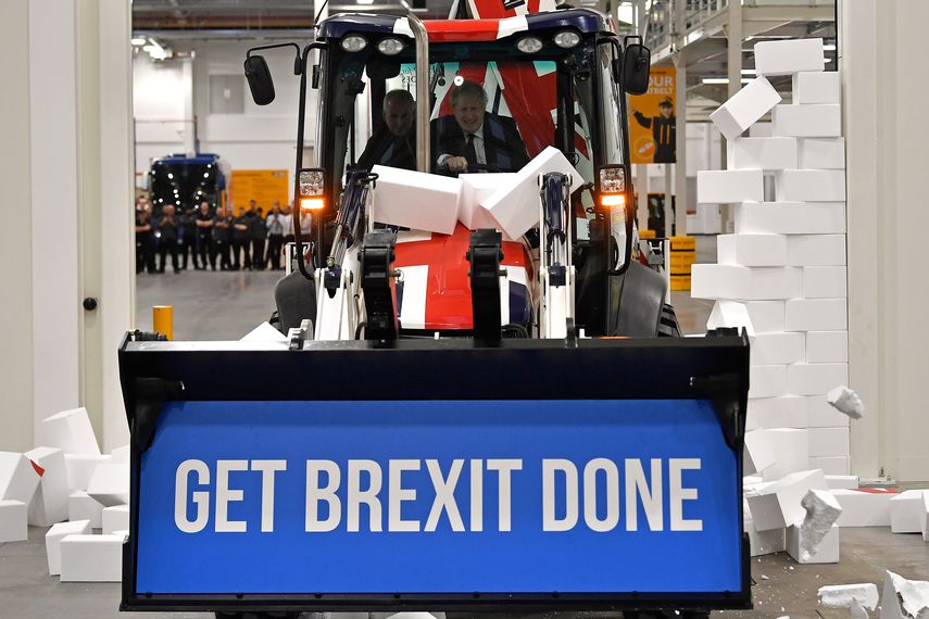 En esta foto de archivo tomada el 10 de diciembre de 2019, el primer ministro británico y líder del partido conservador Boris Johnson conduce un JCB con el tema de la bandera de la Unión, con las palabras Get Brexit Done dentro del cubo de la excavadora, a través de una pared falsa con la palabra GRIDLOCK.&nbsp; &nbsp;