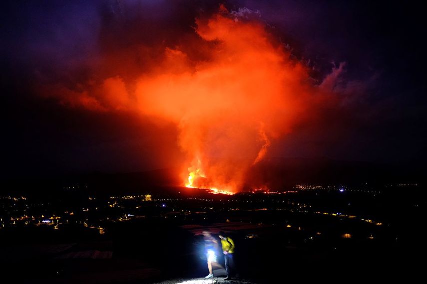 Dos personas caminan durante la noche mientras un volcán expulsa lava, en La Palma, Islas Canarias, el 25 de septiembre de 2021.