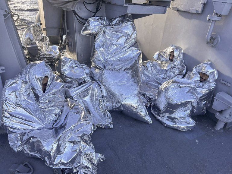 En esta foto distribuida por la Guardia Costera griega, algunos de los nueve sobrevivientes de un naufragio de migrantes, hallados en un islote deshabitado, se tapan con mantas térmicas en un buque guardacostas griego en el mar Egeo, Grecia, martes 1 de noviembre de 2022. 