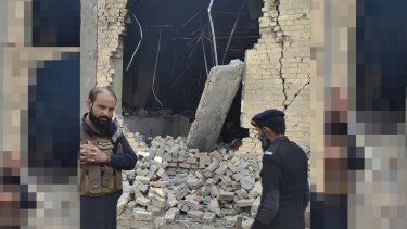 Agentes de policía examinan los daños en el sitio de un ataque con bomba a un cuartel de policía en las afueras de Dera Ismail Khan, Pakistán, martes de diciembre de 2023. El suicida que estrelló su vehículo contra el portón de un cuartel de la policía en el noroeste de Pakistán llevaba 120 kilos (264 libras) de explosivos, dijeron las autoridades el miércoles 13 de diciembre de 2023. El atentado de la víspera provocó la muerte de 23 agentes y heridas a 32.