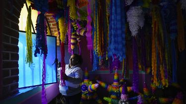 Papeles de colores cortados para decorar piñatas, una artesanía navideña, colgados en un negocio familiar en Acolman, al norte de Ciudad de México, el miércoles 13 de diciembre de 2023. Hay infinitos diseños, desde personajes de Disney a figuras políticas, pero la forma tradicional de la piñata es de una esfera con siete picos, como una estrella.