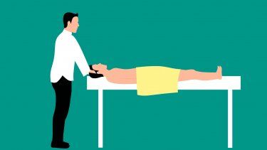 Especialista inicia ejercicio de terapia física moviendo la cabeza del paciente.&nbsp;