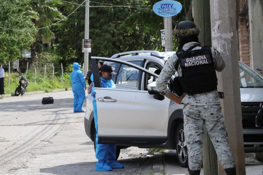 Un agente de la Guardia Nacional mexicana observa a un forense mientras investiga la escena del crimen en la que fue asesinado Fernando García Fernández, representante de la Fiscalía General de la República en el estado de Guerrero, por un hombre armado, en Chilpancingo, México, el martes 12 de septiembre de 2023. 
