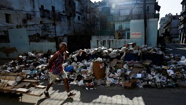Un hombre transporta trozos de madera cerca de una gran cantidad de basura en una calle de La Habana el 21 de agosto de 2024. La Habana acumula más de 30.000 metros cúbicos de basura diarios, siete mil más que hace un año, según cifras oficiales.