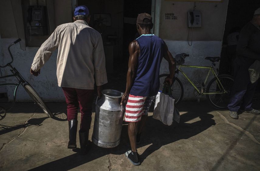 Hombres cargan un tanque de leche para entregar en una bodega estatal en San Nicolás, Cuba