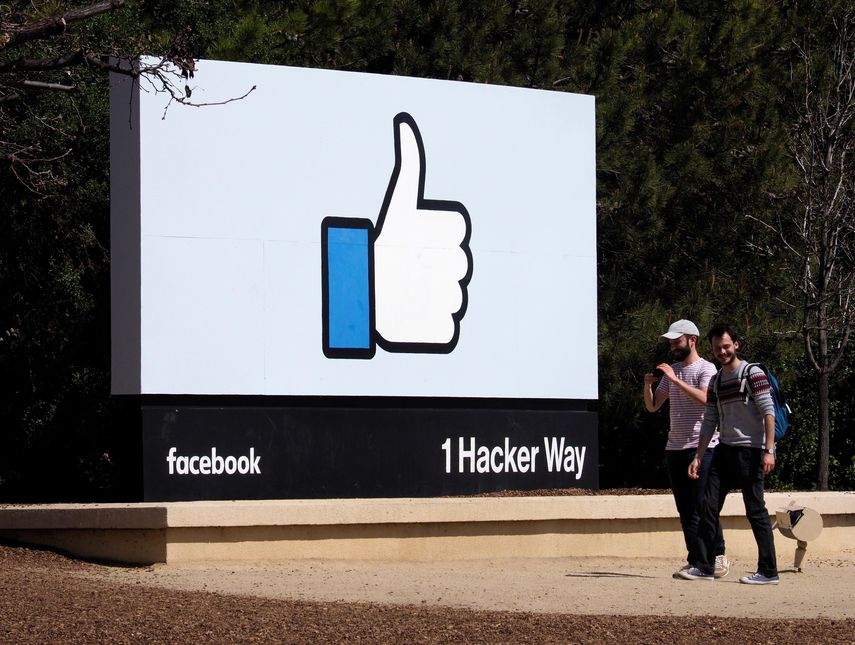 Dos hombres caminan junto a un icono de&nbsp;Facebook&nbsp;en Menlo Park, California, el 30 de marzo del 2018.&nbsp;