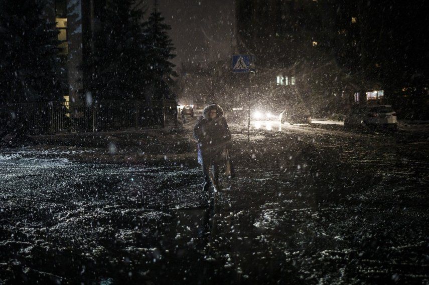 Una mujer cruza una calle durante una nevada, en pleno apagón en Kiev, Ucrania, el 16 de diciembre de 2022.&nbsp;
