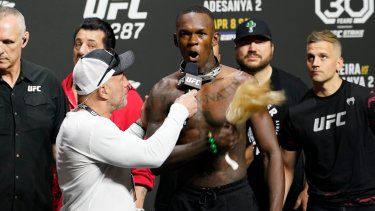 El comentarista de UFC Joe Rogan, al frente a la izquierda, escucha a Israel Adesanya después de un pesaje ceremonial el viernes 7 de abril de 2023 en Miami. Adesanya enfrentó y noqueó al campeón de peso mediano de UFC 287, Alex Pereira, el sábado.&nbsp;