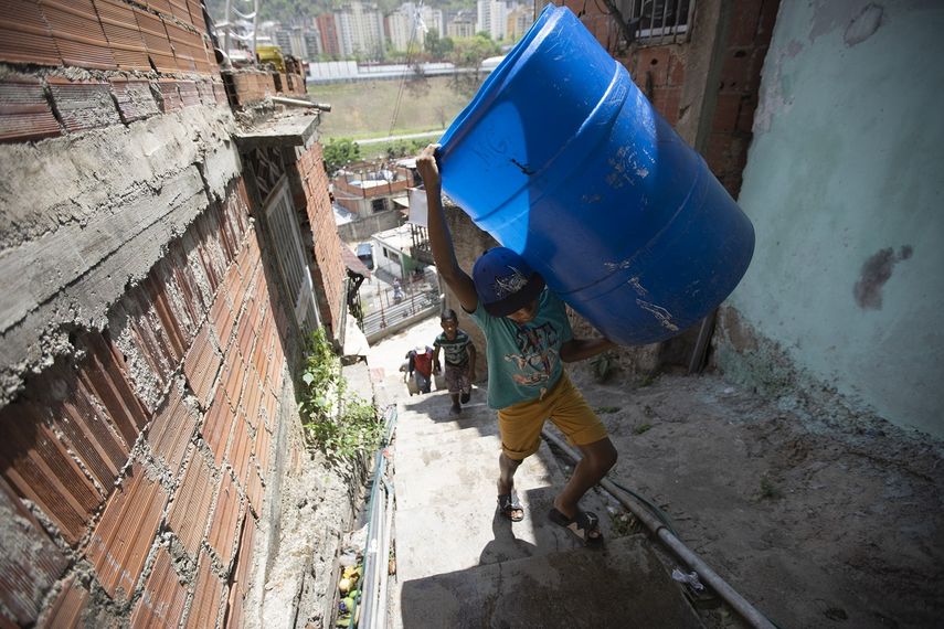 Un niño sube unas escaleras cargado con dos recipientes vacíos que llenará con el agua suministrada por un camión cisterna del gobierno, en el vecindario de Petare, en Caracas, Venezuela, el 15 de junio de 2020. El colapso económico de Venezuela ha dejado a la mayoría de los hogares sin un suministro de agua corriente confiable.&nbsp;