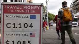 Peatones pasan junto a un cartel con tipos de cambio ante un establecimiento en Londres.