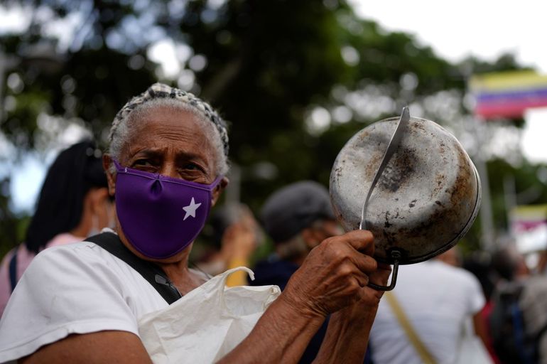 Una manifestante golpea una olla para referirse al hambre durante una manifestación de trabajadores públicos activos y jubilados, incluidos maestros, que exigen mejores salarios y el resto de su bono de vacaciones que dicen fue pagado parcialmente, mientras marchan hacia el Ministerio de Trabajo en Caracas, Venezuela, el martes 2 de agosto de 2022.