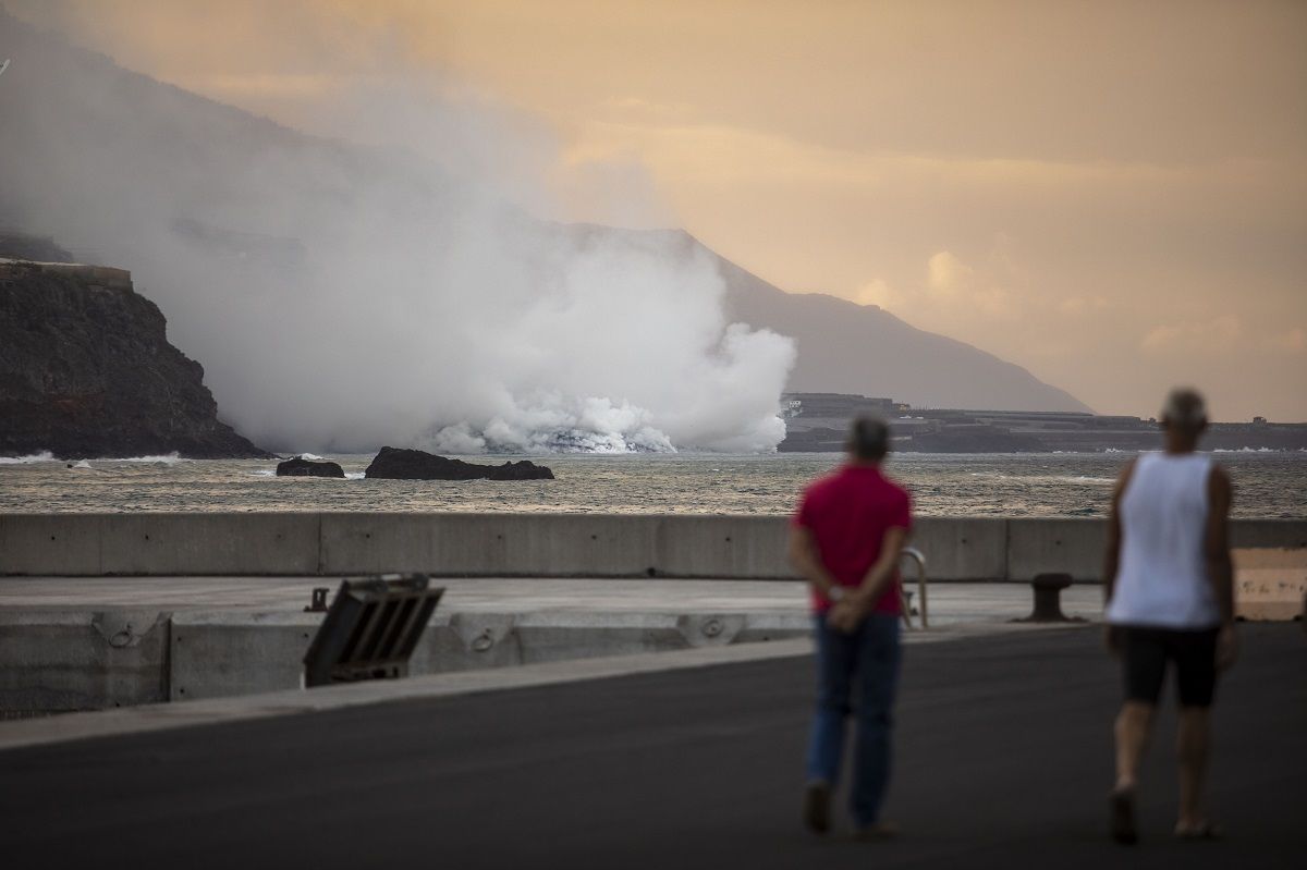 Dos personas observan la columna de humo y la lava del volcán de Cumbre Vieja a su llegada al Océano Atlántico, a 29 de septiembre de 2021, en La Palma, Santa Cruz de Tenerife, Islas Canarias, (España). La lava del volcán, que entró el 19 de septiembre en erupción, ha provocado un delta de lava que poco a poco va ganando terreno al mar a su llegada al Océano Atlántico. Las autoridades recomiendan permanecer al menos a 3,5 km de la zona ya que la entrada en contacto de la lava con el mar forma nubes blancas de vapor de agua y gases nocivos para la salud. Dos personas observan la columna de humo y la lava del volcán de Cumbre Vieja a su llegada al Océano Atlántico, a 29 de septiembre de 2021, en La Palma, Santa Cruz de Tenerife, Islas Canarias, (España). La lava del volcán, que entró el 19 de septiembre en erupción, ha provocado un delta de lava que poco a poco va ganando terreno al mar a su llegada al Océano Atlántico. Las autoridades recomiendan permanecer al menos a 3,5 km de la zona ya que la entrada en contacto de la lava con el mar forma nubes blancas de vapor de agua y gases nocivos para la salud.