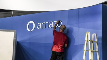Un trabajador ajusta un letrero de Amazon. 