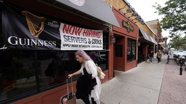Una persona camina con su equipaje junto a un anuncio de empleos vacantes en un restaurante en Sioux Falls, Dakota del Sur.&nbsp;