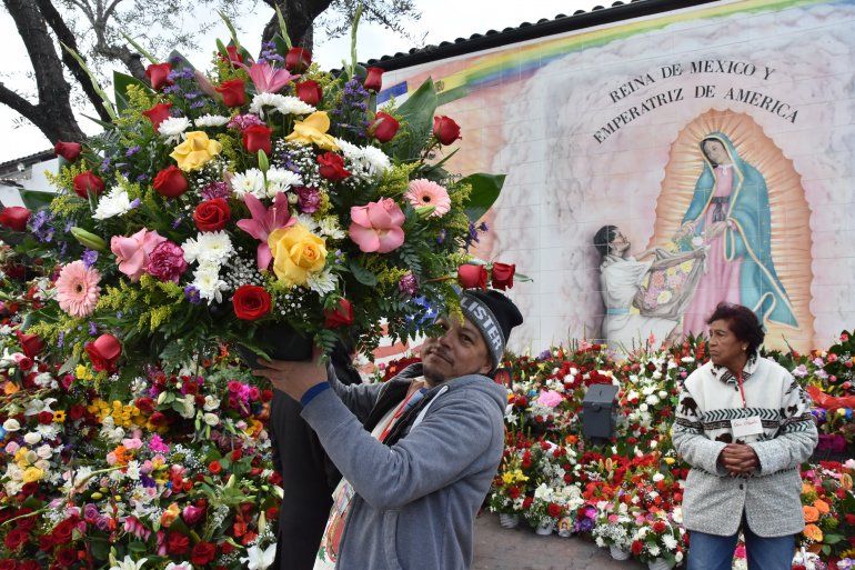 Los voluntarios Andrés Aviña y Dora Obando acomodan arreglos florales en frente de un mural con la imagen de la&nbsp;virgen&nbsp;de&nbsp;Guadalupe&nbsp;este miércoles 12 de diciembre en el centro histórico de Los Ángeles.