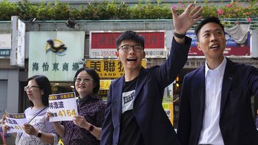 El candidato ganador de las elecciones locales Kelvin Lam, a la derecha, junto al activista prodemocracia Joshua Wong, segundo por la derecha, saludan a la gente y dan gracias por el apoyo en la estación South Horizons de Hong Kong, el lunes de noviembre de 2019.&nbsp;