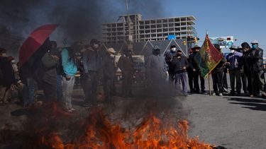 Manifestantes con tapabocas por el nuevo coronavirus queman un neumático durante una protesta contra el aplazamiento de las próximas elecciones presidenciales en El Alto, Bolivia. La máxima autoridad electoral de Bolivia retrasó las elecciones presidenciales&nbsp;por la pandemia.