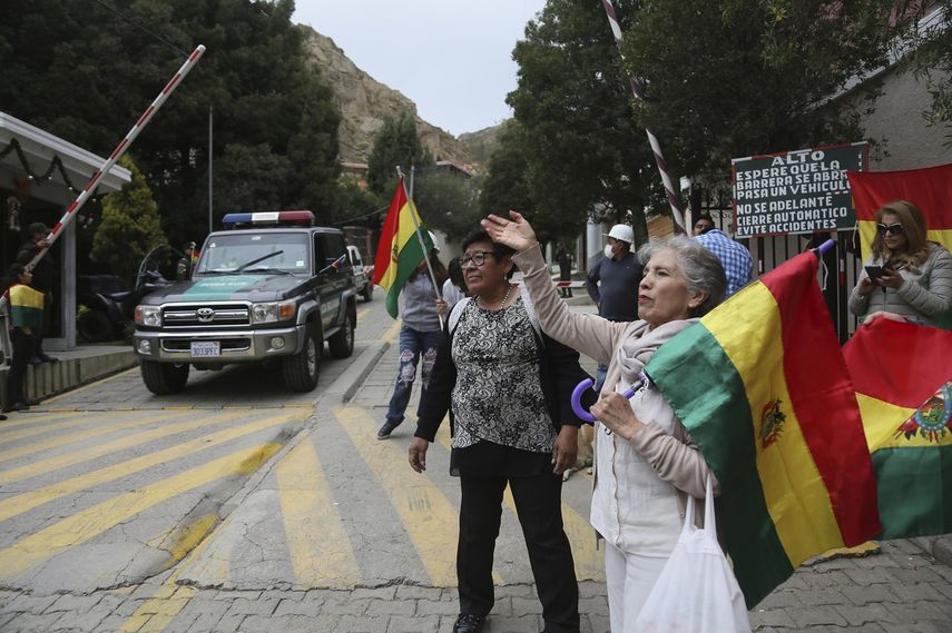Varias personas protestan en la entrada que conduce a la embajada mexicana para asegurarse de que nueve exfuncionarios del gobierno del depuesto presidente boliviano Evo Morales, que se han refugiado en el interior, no salgan del pa&iacute;s, en La Paz, Bolivia, el lunes 30 de diciembre de 2019.&nbsp;