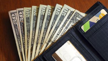 Imagen de billetes de 20, 50 y un dólar en una billetera.
